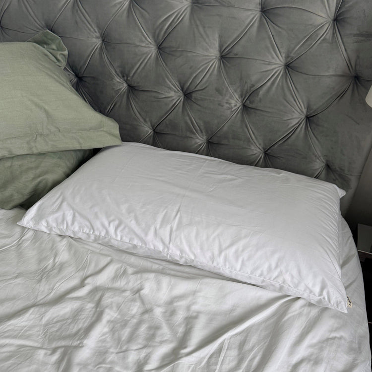 White pillow on a bed with a tufted gray headboard